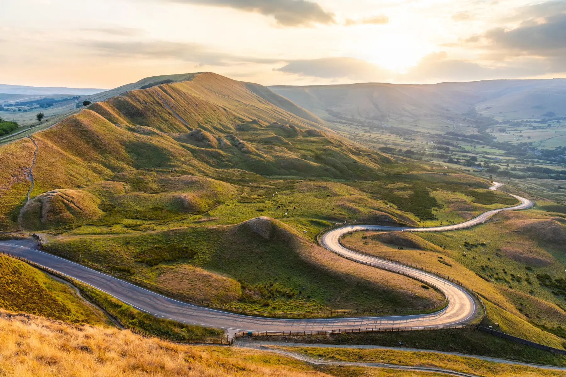 Beautiful winding road and hills at sunset in the Peak District Landscape view with golden light in the UK Nature and travel concepts, background ready image